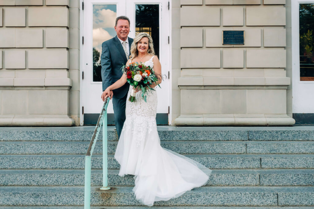 A bride and groom standing on the steps of a historic building taken by Prescott wedding photographer Melissa Byrne.