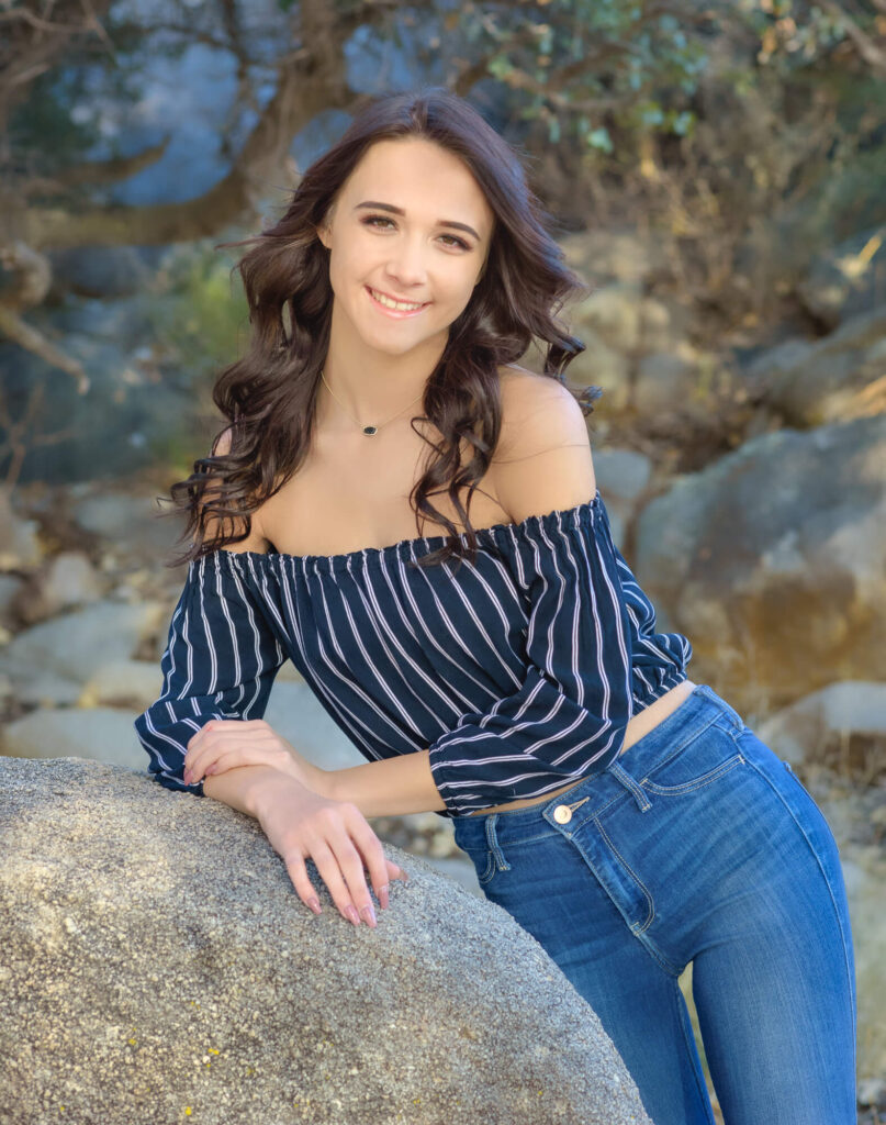 High school girl leaning against a rock  at Willow Lake in a senior photography in Prescott, AZ session by Melissa Byrne Portrait Photography.