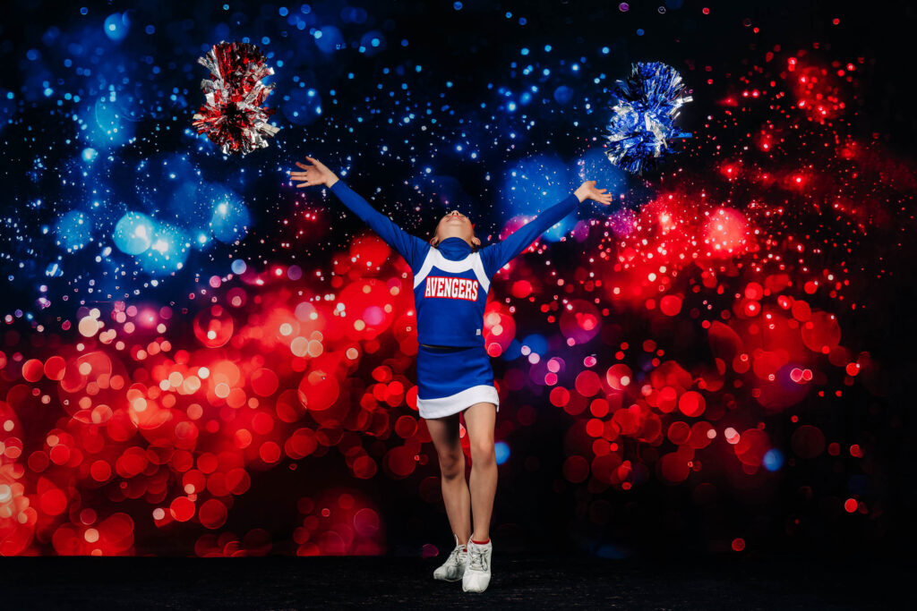 Cheer in Prescott, AZ includes sideline cheer as shown in this photo of a football cheerleader throwing her pom poms by Melissa Byrne Portrait Photography.