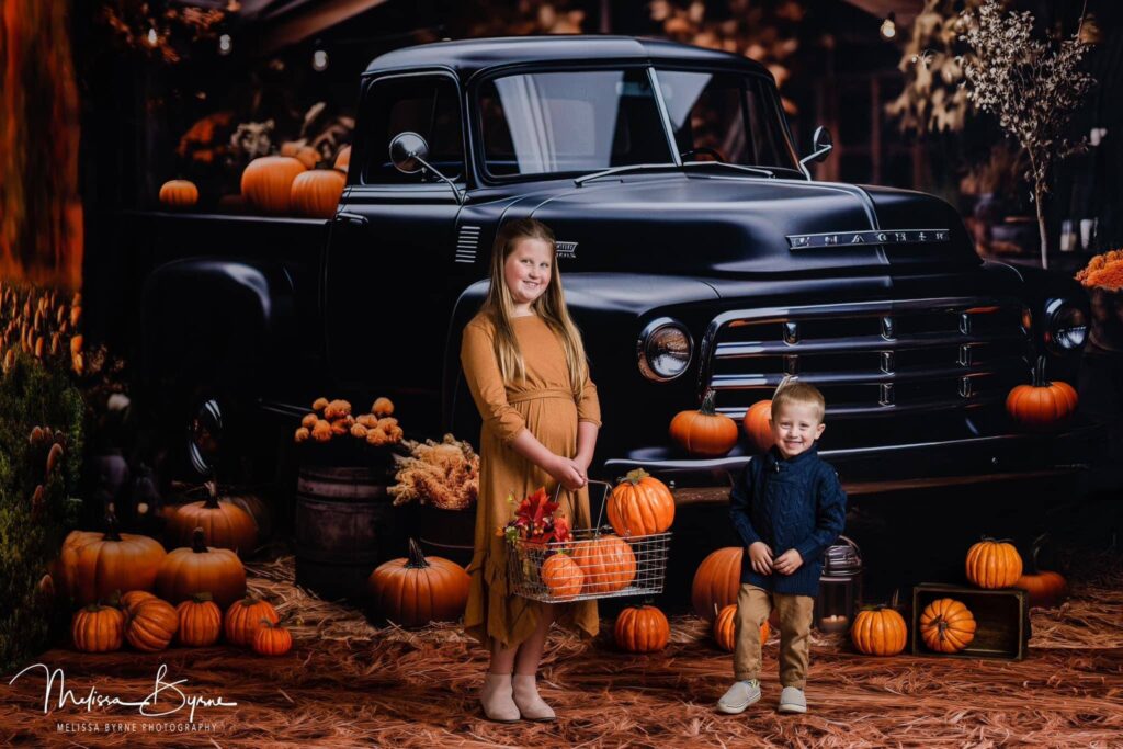 Kids in front of a vintage truck in a Fall mini session scene.